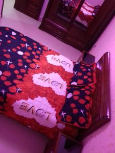a bedroom with a bed with a red and black blanket at إقامة المول in Fort de lʼEau