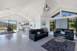a living room with two black couches and a table at Whangaroa Casa Roca House in Kaeo