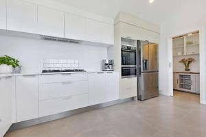 a kitchen with white cabinets and stainless steel appliances at Whangaroa Casa Roca House in Kaeo