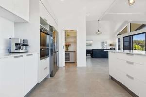 a kitchen with white cabinets and a living room at Whangaroa Casa Roca House in Kaeo