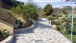 a stone walkway with trees and flowers next to a building at Galini Apartments in Palekastron
