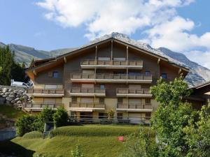 a large building with a mountain in the background at Appt 3 pièces, 6 couchages, proche commerces et pistes, parking inclus, animaux admis - FR-1-241-177 in Le Grand-Bornand