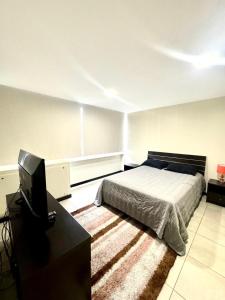 a bedroom with a bed and a desk and a television at Love Apartment in Guayaquil