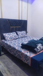 a bed with a blue bedspread and pillows on it at The 104-H in Faisalabad