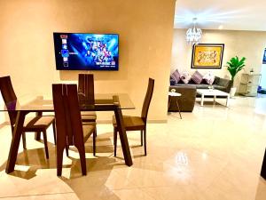 a living room with a table and a tv on the wall at Appartement avec vue sur parc et Wifi 100 Mo illimité ! in Fez