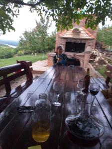 a man sitting on a wooden table with wine glasses at Ranč Petar Alavanja Banstol in Sremski Karlovci