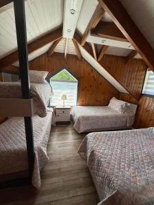 a attic room with three beds and a window at Hotel y Cabañas Molino Viejo in Puerto Varas +52 photos
