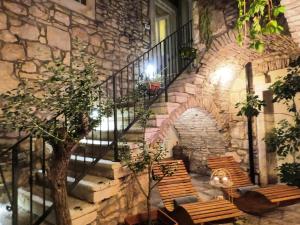 a stone staircase with wooden chairs and a stone wall at Stone House Hedonia in Blato