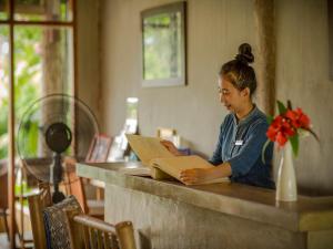 a woman sitting at a counter reading a book at My Dream Boutique Resort in Luang Prabang