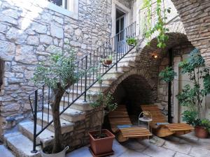 a stone building with stairs and benches in front of it at Stone House Hedonia in Blato