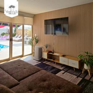 a bedroom with a large bed and a tv on the wall at The White Palm Villa & Pool in Khon Kaen