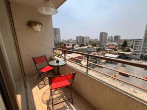 two chairs and a table on a balcony with a view of a city at Habitaciones con C in Concepción