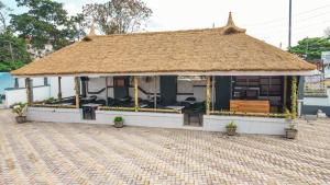 a small building with a thatched roof with a bench at Royal Modak Resort & Hotel in Ibadan