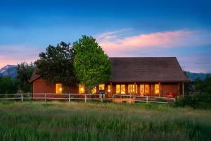 a wooden house with lights on in a field at Upscale Hot Tub Wildlife Views in Victor