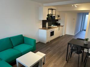 a living room with a green couch and a kitchen at Apartmány ASTRA in Cheb