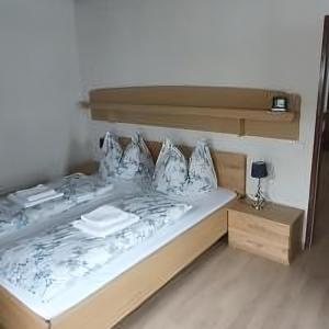 a bed with a wooden headboard and pillows at Apartment Haus Starfach in Döbriach