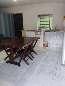 a kitchen with a wooden table and some chairs at Recanto Sebold in Guaratuba