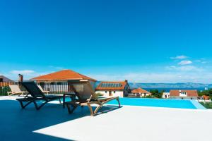a villa with a swimming pool and two chairs on the roof at Vila JELSANA in Jelsa