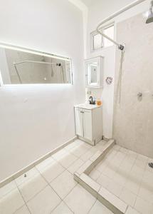 a white bathroom with a shower and a sink at Baja Cabo Hostal Arenal in Cabo San Lucas