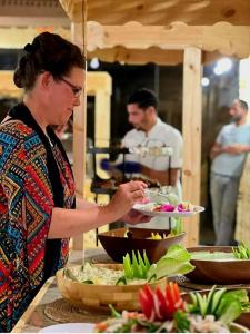 a woman holding a plate of food at a buffet at Wadi rum camp in Wadi Rum