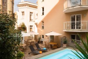 a courtyard with a pool and chairs and tables and umbrellas at Villa d'Estelle in Cannes