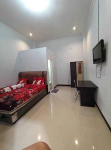a room with a bed and a desk and a tv at Hotel Raudah Kapuas in Kualakapuas