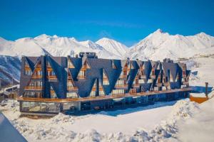 a building in the snow with mountains in the background at Mountain View Apartment Near Ski Slopes Gudauri in Kʼumlistsʼikhe