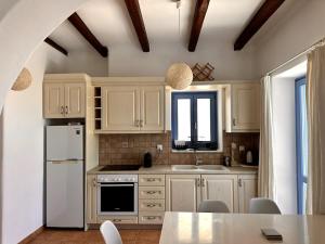 a kitchen with white cabinets and a white refrigerator at Sea View Cycladic Home in Santa Maria
