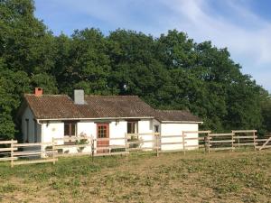 a white house in a field next to a fence at La Bergerie in Froid-Chapelle