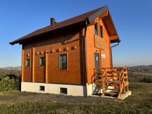 a small wooden house with a porch and a staircase at Kuća za odmor Kiara in Kolarec
