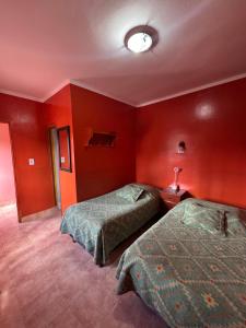 two beds in a hotel room with red walls at Sumaq Samay in San Antonio de los Cobres +3 photos