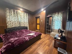 a bedroom with a purple bed and wooden floors at The sameer resort in Anantnāg