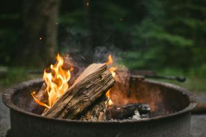 a fire pit with a piece of wood and flames at Oak - The Nook Lodges in Wrenbury