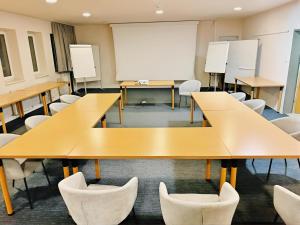 a classroom with tables and chairs and a whiteboard at Hotel Hecher in Wolfsberg