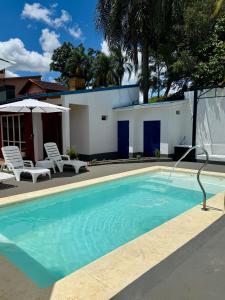 a swimming pool with two chairs and a house at Azul Hotel Oberá in Oberá