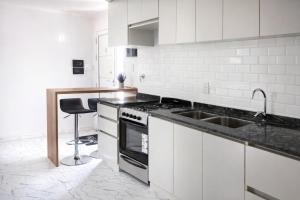 a white kitchen with a sink and a stove at Aura Apart in Reconquista