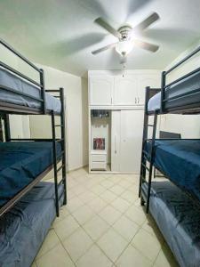 a room with three bunk beds and a ceiling fan at Baja Cabo Hostal Arenal in Cabo San Lucas +7 photos