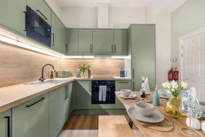 a kitchen with green cabinets and a wooden table at The Sauchie in Glasgow