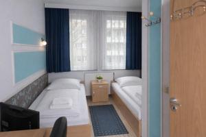 ein kleines Zimmer mit zwei Betten und einem Fenster in der Unterkunft Pension Central Nuernberg-Fuerth in Fürth