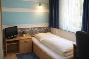ein kleines Zimmer mit einem Bett und einem Fernseher in der Unterkunft Pension Central Nuernberg-Fuerth in Fürth