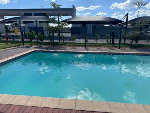 a swimming pool in front of a house at Habitat Kappa Alexio in Gaborone