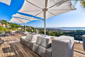 a patio with a couch and an umbrella at Villa Bambou bei Cannes mit Blick auf Cap Antibes in Vallauris