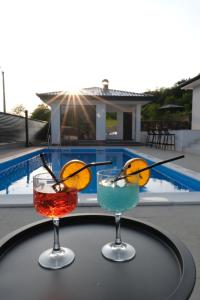 two cocktails sitting on a table next to a pool at Luxury Villa JAKOV in Banja Luka