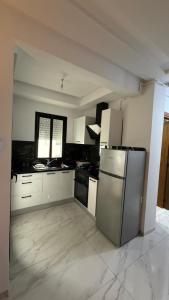 a kitchen with a stainless steel refrigerator and white cabinets at La perle in Sukrah