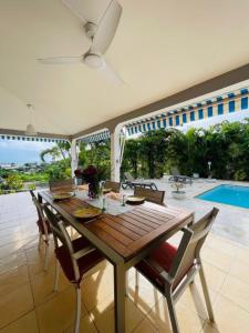 a dining room with a table and chairs and a pool at Villa Amaryllis in Le Gosier