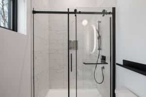 a shower with a glass door in a bathroom at Chalet Peak Tremblant: Your Mountain Escape. in La Conception +99 photos