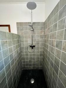 a bathroom with a shower with a tiled wall at Bungalow sur la plage in Le Carbet