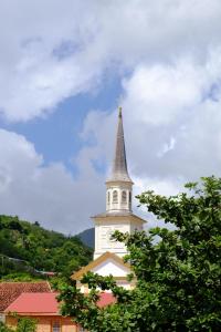 a white steeple of a church with a tower at Bungalow sur la plage in Le Carbet