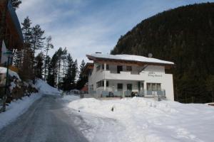 a house in the snow next to a road at Apart Raphael in Niederthai