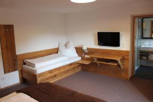 a room with a bench with a tv and a table at Haus Martina Buchhammer in Fendels